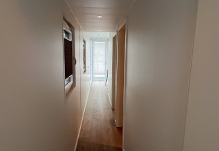 Corridoio stretto con pavimento in legno e pareti bianche su una houseboat a Marina Lemmer, Olanda.