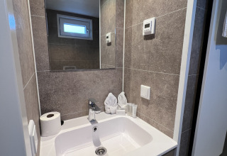Moderne badeværelsevask med spejl, toiletpapir og foldede håndklæder på et husbåd i Lemmer, Holland.