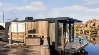 Moderne woonboot aangemeerd aan Marina Lemmer in Nederland, met terras en zitplaats aan het water.