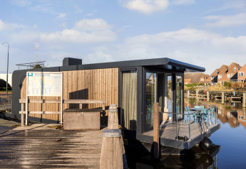 Modernes Hausboot in der Marina Lemmer, Niederlande, am Steg mit Terrasse und Blick auf das Wasser.