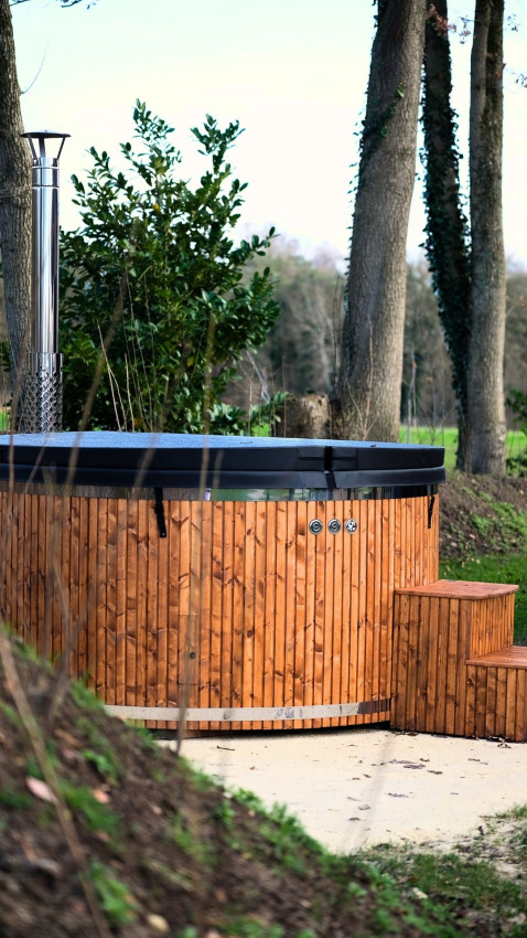 Bain à remous extérieur en bois avec cheminée, près des arbres à Wood Cottage, camping de Witte Berg, Pays-Bas.