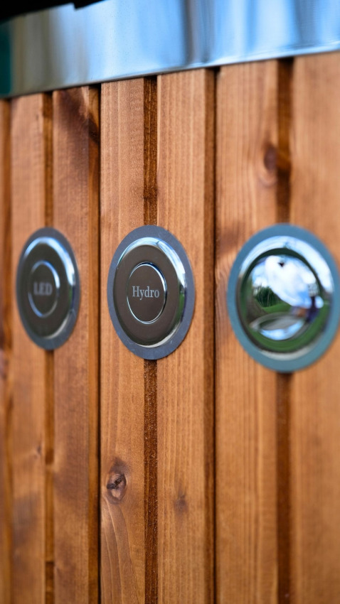 Close-up of LED and Hydro metal buttons on wood paneling at Wood Cottage with hot tub in the Netherlands.