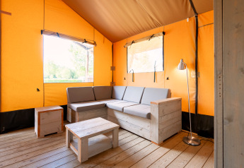Interieur van de Nomad safaritent met houten bank en moderne inrichting op Camping Vilanova Park, Spanje.