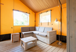 Interno della tenda safari Nomad con divano in legno e arredo moderno al campeggio Vilanova Park, Spagna.