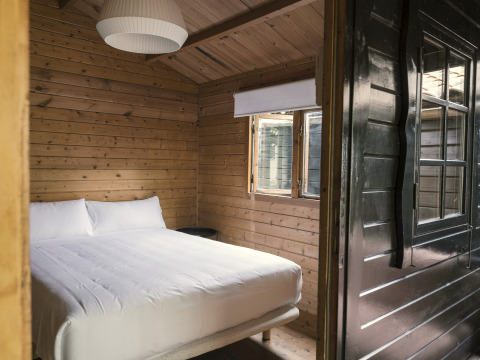 Cozy wooden tiny house bedroom with a double bed and window at Wecamp Cudillero, Spain.