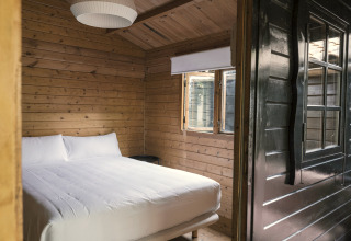Cozy wooden tiny house bedroom with a double bed and window at Wecamp Cudillero, Spain.