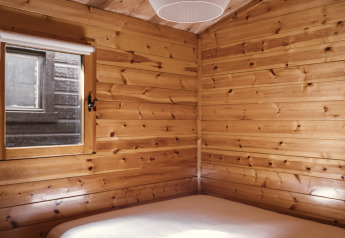 Holzverkleidetes Schlafzimmer mit Doppelbett und Fenster in Bungalow Basic Family Plus bei Wecamp Cudillero, Spanien.