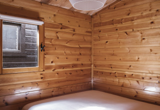 Dormitorio de madera acogedor con cama doble y ventana en Bungalow Basic Family Plus de Wecamp Cudillero, España.