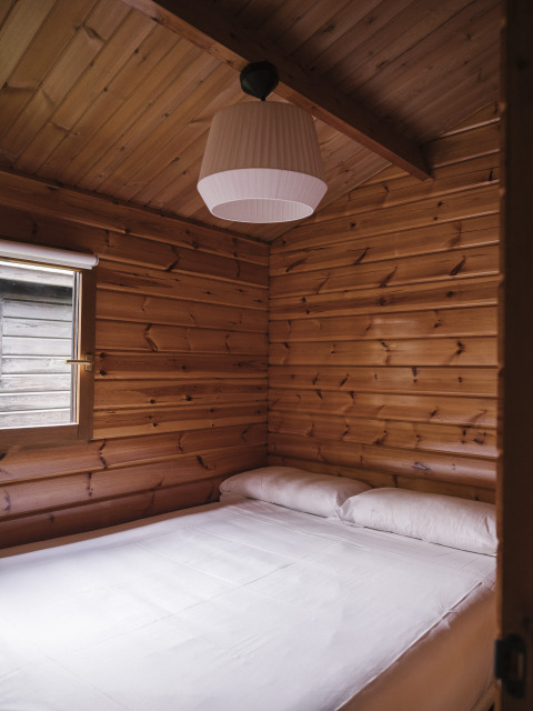 Dormitorio con paredes de madera y cama doble en Bungalow Basic Family de Wecamp Cudillero, España.