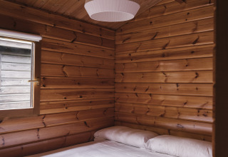 Dormitorio con paredes de madera y cama doble en Bungalow Basic Family de Wecamp Cudillero, España.