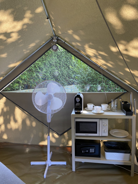 Innenraum eines Safari-Zelts mit Ventilator, Mikrowelle und Kaffeemaschine im Wecamp Cudillero, Spanien.