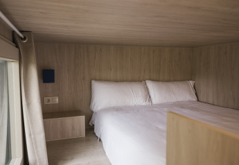 Chambre confortable du Tiny Home «Family Wood» à Wecamp Cudillero en Espagne, murs en bois clair et grand lit.