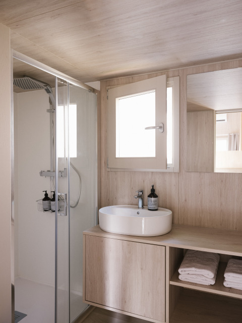 Modern badkamerinterieur in Tiny Home 'Family Wood' bij Wecamp Cudillero, Spanje, met douche en wastafel.