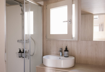 Salle de bain moderne du Tiny Home 'Family Wood' à Wecamp Cudillero, Espagne, avec douche et vasque en bois.