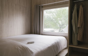 Lichte slaapkamer met dubbel bed, groot raam en kleerkast in Tiny Home «Family Wood» bij Wecamp Cudillero, Spanje.