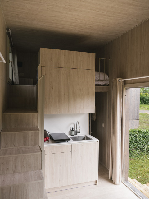 Interieur van Tiny Home 'Family Wood' bij Wecamp Cudillero in Spanje, met moderne compacte keuken.