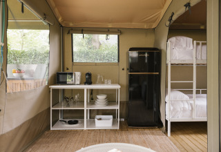 Vue intérieure de la tente Cottage Family à Wecamp Cudillero en Espagne, avec cuisine et lits superposés.