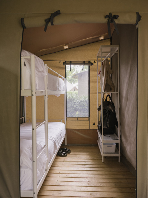 Vue intérieure d’une Cottage Family Tent avec lits superposés et rangement à Wecamp Cudillero, Espagne.