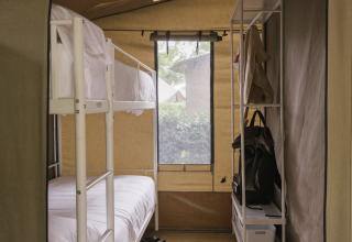 Vue intérieure d’une Cottage Family Tent avec lits superposés et rangement à Wecamp Cudillero, Espagne.