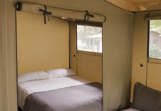 Intérieur d’une tente safari avec lit double, canapé et fenêtres au Cottage Family Tent de Wecamp Cudillero, Espagne.