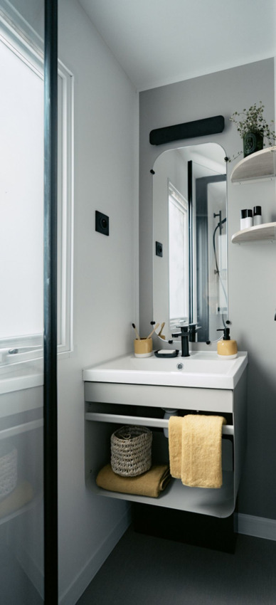 Moderne badkamer met gele handdoek en subtiele inrichting in Next L Titania, Trasimeno Glamping Resort, Italië.