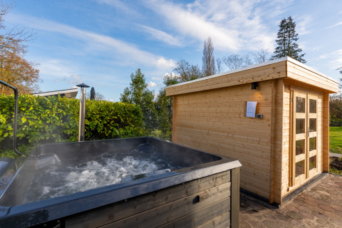 Buiten bubbelbad en sauna bij de Forest Lodge in Holiday center 't Schuttenbelt, Nederland op zonnige dag.
