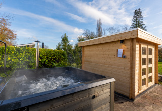 Buiten bubbelbad en sauna bij de Forest Lodge in Holiday center 't Schuttenbelt, Nederland op zonnige dag.
