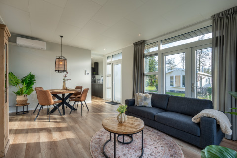 Moderne woonkamer in de Forest lodge bij Holiday center 't Schuttenbelt in Nederland, met grote ramen.