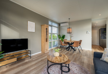 Moderne woon- en eetruimte in Forest Lodge, Holiday center 't Schuttenbelt in Nederland, met houten meubels.