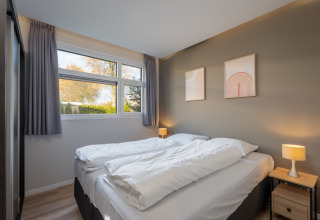 Camera da letto al Forest lodge presso il centro vacanze 't Schuttenbelt, Paesi Bassi, con letto e finestra.