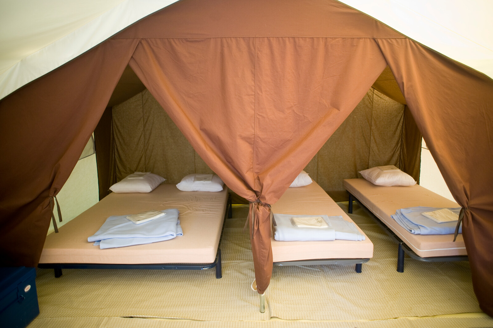 Binnenkant van een safaritent met vier opgemaakte bedden bij Tent Classic in Huttopia Lac d'Aiguebelette, Frankrijk.
