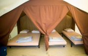 Binnenin een safaritent met vier opgemaakte bedden bij Tent Classic in Huttopia Lac d’Aiguebelette, Frankrijk.