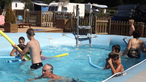 Bambini e adulti giocano nella piscina all’aperto al Flower Camping de la Trye in Hauts-de-France, Francia.