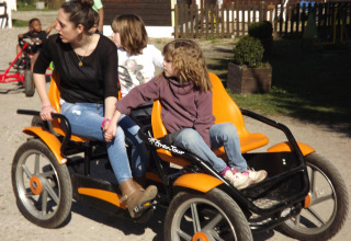 Donna e due bambini si divertono su un kart a pedali a Flower Camping de la Trye, Hauts-de-France, Francia.