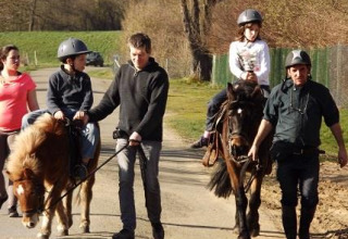Niños disfrutan de paseos en pony guiados por adultos en Flower Camping de la Trye, Hauts-de-France, Francia.