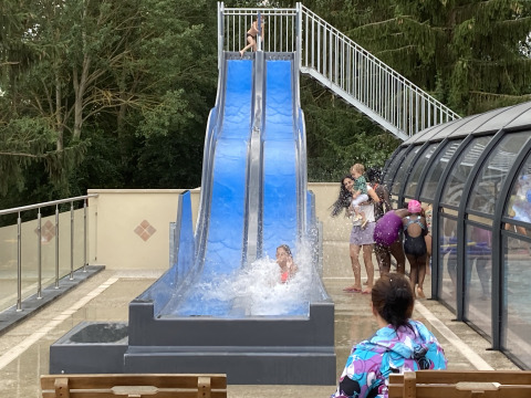 Bambini giocano su uno scivolo d’acqua blu al Flower Camping de la Trye in Hauts-de-France, Francia.