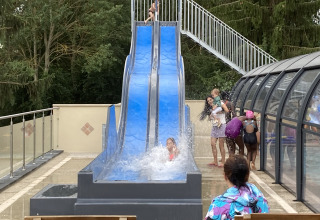 Bambini giocano su uno scivolo d’acqua blu al Flower Camping de la Trye in Hauts-de-France, Francia.