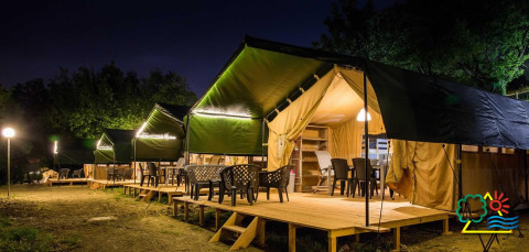 Aftensstemning ved glamping-telte på Centro Vacanze San Marino-feriepark, omgivet af træer og natur.