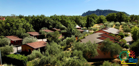 Vista del Centro Vacanze San Marino, con cabañas de madera y vegetación exuberante, rodeado de colinas verdes.