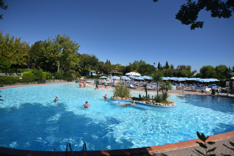 Piscina al aire libre con personas nadando, tumbonas y sombrillas en Centro Vacanze San Marino.