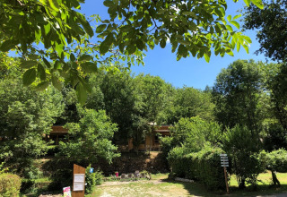 Leafy camping site at Moulin de Chaules holiday park in Auvergne-Rhône-Alpes, France, on a bright sunny day.
