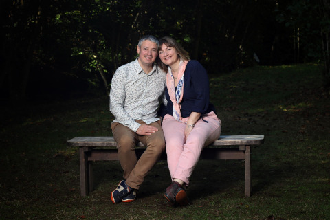 A smiling couple sitting together on a bench at Campsite Moulin de Chaules in Auvergne-Rhône-Alpes, France.