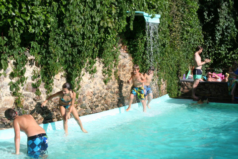 Bambini giocano in piscina con cascata al campeggio Moulin de Chaules, Alvernia-Rodano-Alpi, Francia.
