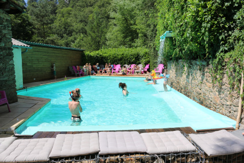 Children and adults swim and play at the outdoor pool at Campsite Moulin de Chaules in Auvergne-Rhône-Alpes.