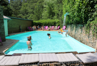 Children and adults swim and play at the outdoor pool at Campsite Moulin de Chaules in Auvergne-Rhône-Alpes.