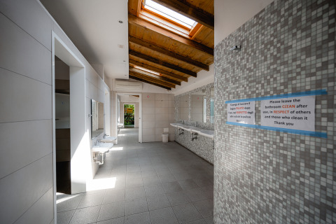 Ruim en licht sanitairgebouw in Centro Vacanze San Marino met spiegels, wastafels en dakramen.