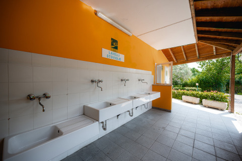 Espace vaisselle extérieur avec éviers blancs et mur orange au Centro Vacanze San Marino, parc de vacances.