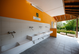 Espace vaisselle extérieur avec éviers blancs et mur orange au Centro Vacanze San Marino, parc de vacances.