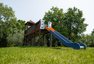 Aire de jeux avec toboggan et structure en bois au Centro Vacanze San Marino, entourée d’arbres verts.