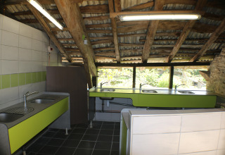 Cucina comune con lavelli multipli e ripiani verdi al campeggio Moulin de Chaules, Alvernia, Francia.